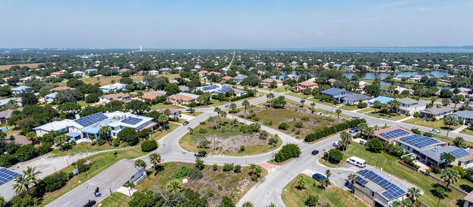 Aerial view of a flat Tampa Bay area Florida neighborhood with rooftop solar panels on homes along palm-lined streets near the water